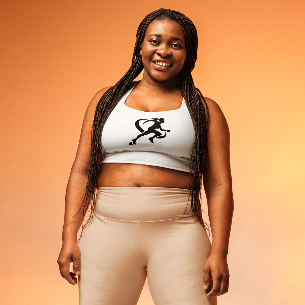 A woman wearing a white longline sports bra with a graphic logo on the front, paired with black activewear pants.