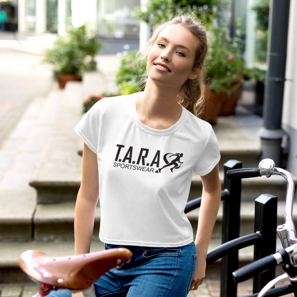 A female model wearing a white crop top with the T.A.R.A Sportswear logo on the front.