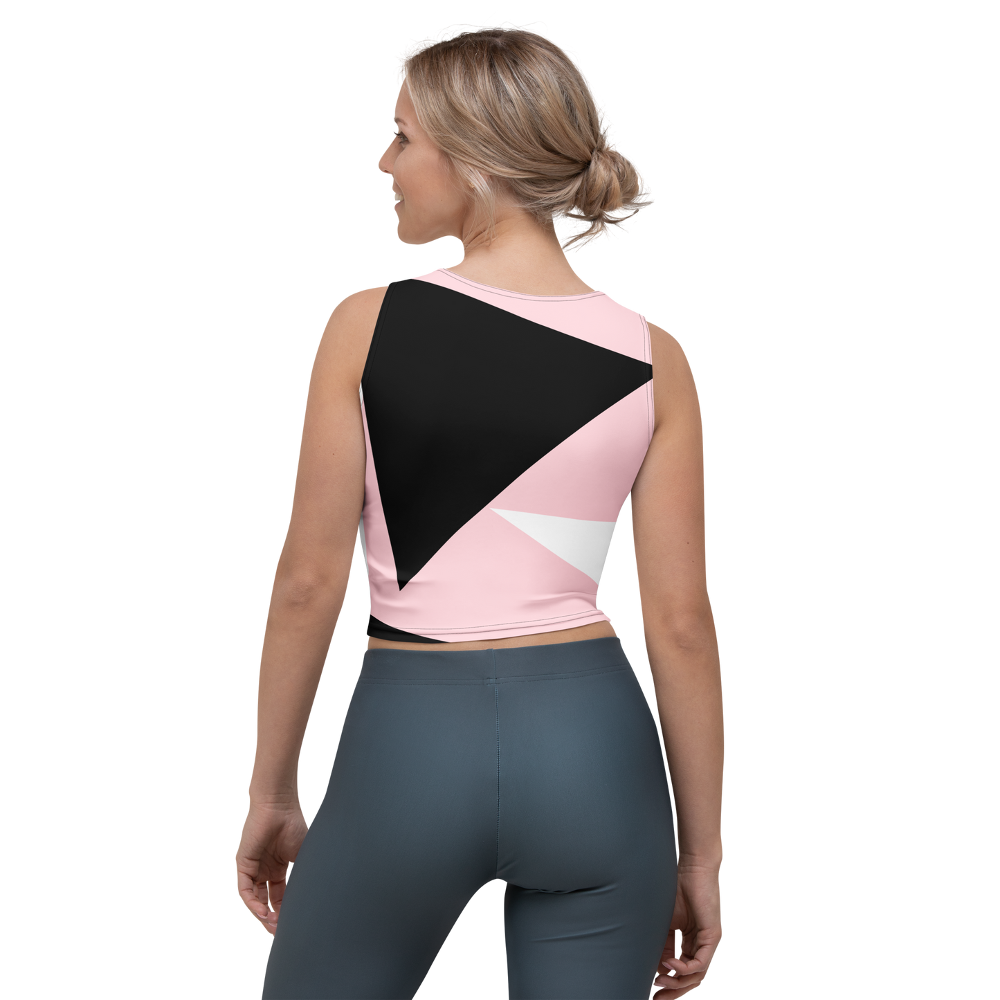 Woman wearing a pink and black sports bra with gray leggings on a white background