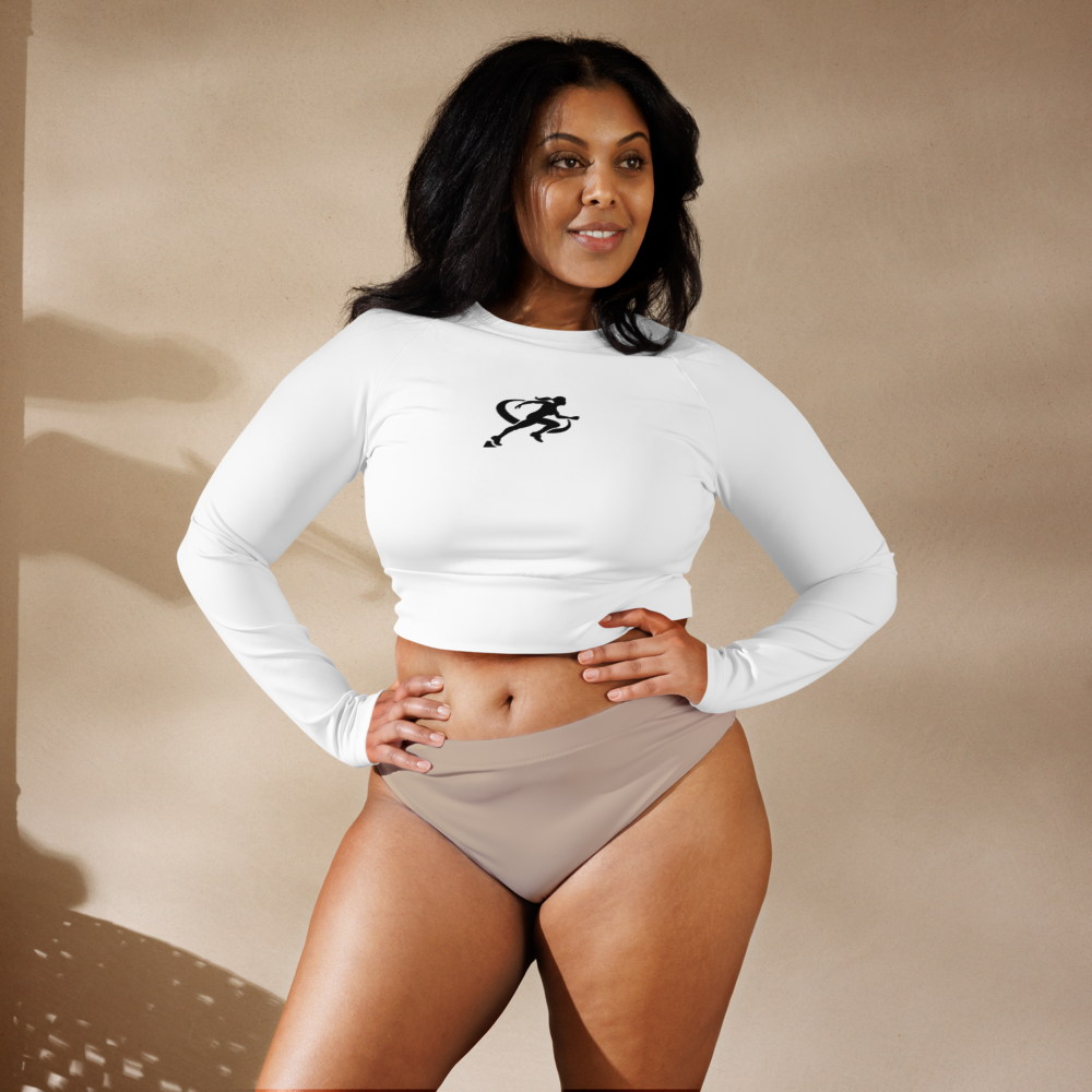 A woman wearing a white long sleeve crop top and light pink bikini bottoms. The crop top has raglan sleeves and a wide, double-layered waistline band.