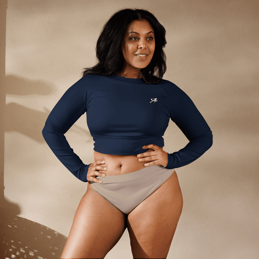 Woman wearing a navy long-sleeve top and beige shorts against a beige background