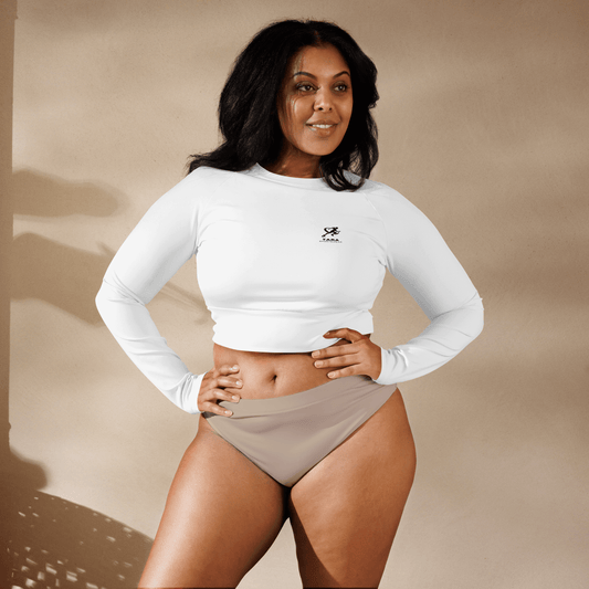 Woman wearing a white long-sleeve crop top and beige high-waisted bikini bottoms against a beige background.