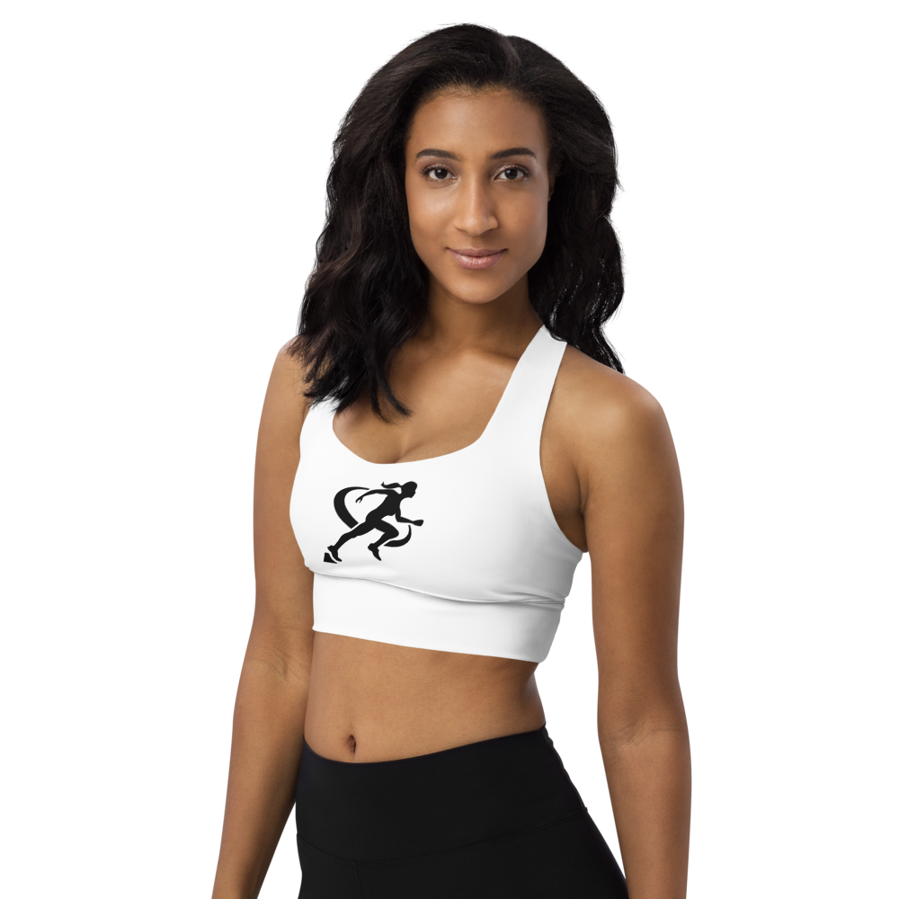 A woman wearing a white longline sports bra with a graphic logo on the front, paired with black activewear pants.