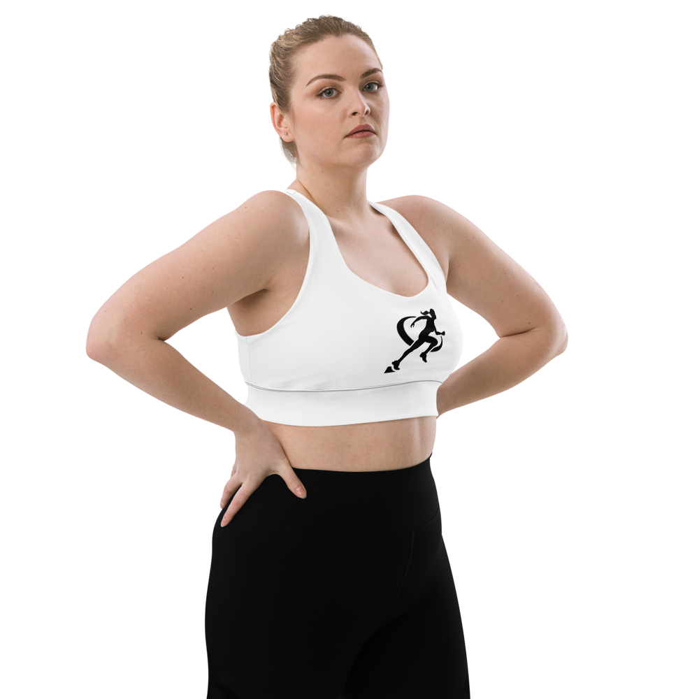 A woman wearing a white longline sports bra with a graphic logo on the front, paired with black activewear pants.