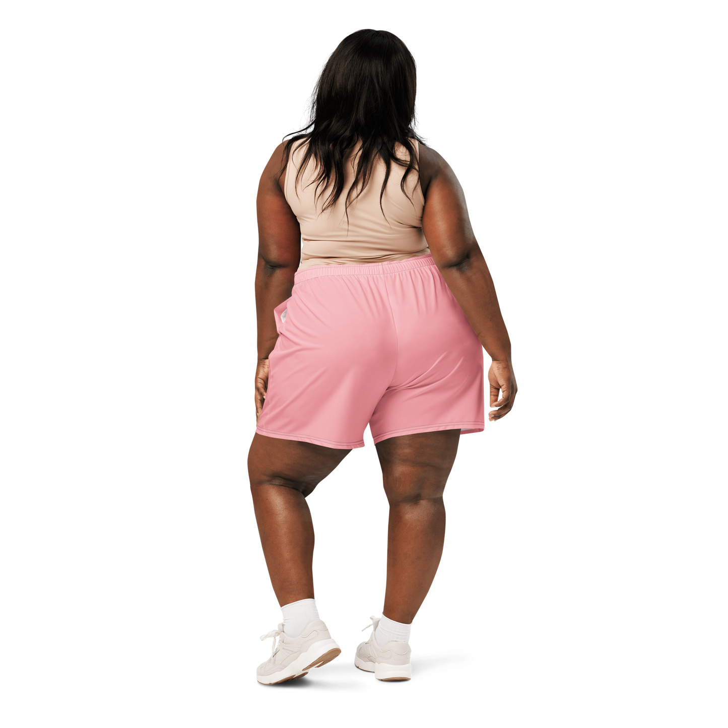 Woman wearing a dark sports bra and pink shorts on a white background