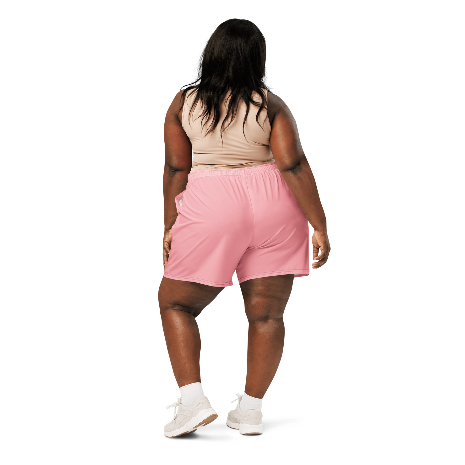 Woman wearing a dark sports bra and pink shorts on a white background