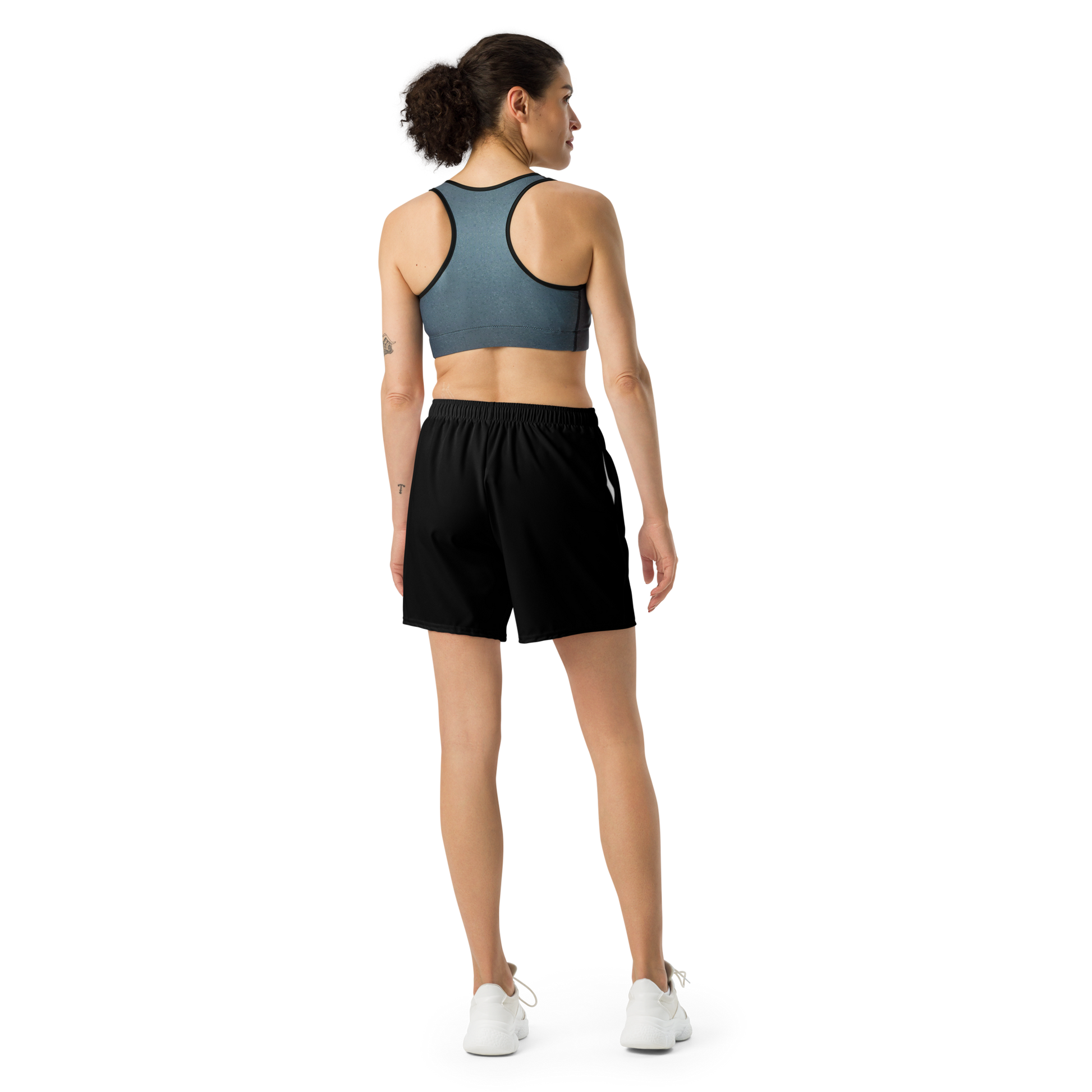 Woman wearing a sports bra and black shorts on a white background
