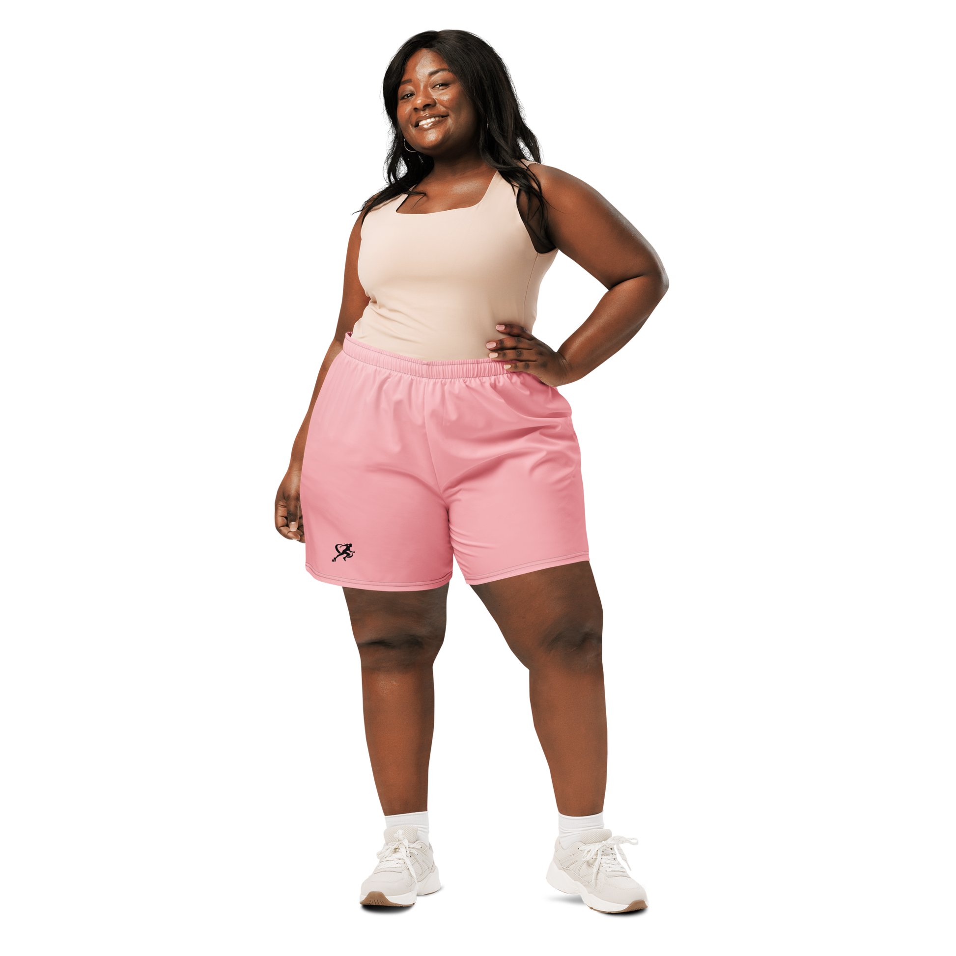 Woman wearing a dark sports bra and pink shorts on a white background