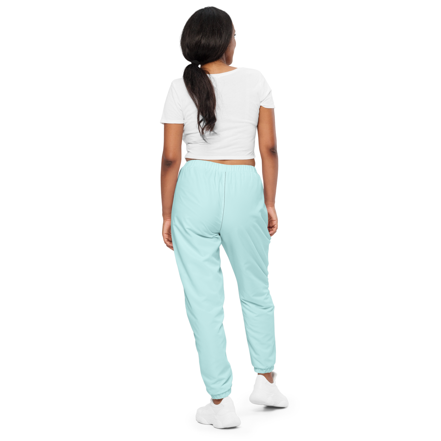 Woman wearing light blue jogger pants and a white crop top on a white background