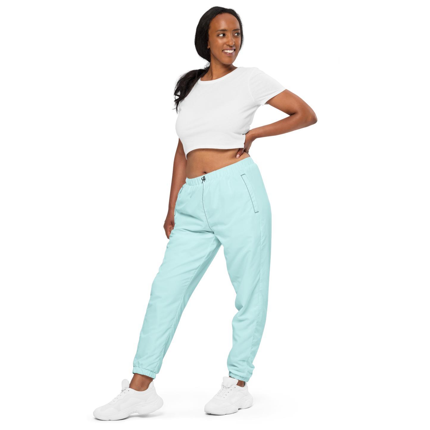 Woman wearing light blue jogger pants and a white crop top on a white background