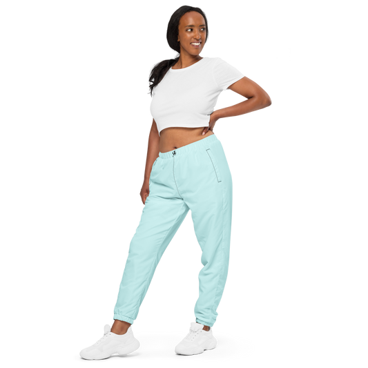 Woman wearing light blue jogger pants and a white crop top on a white background