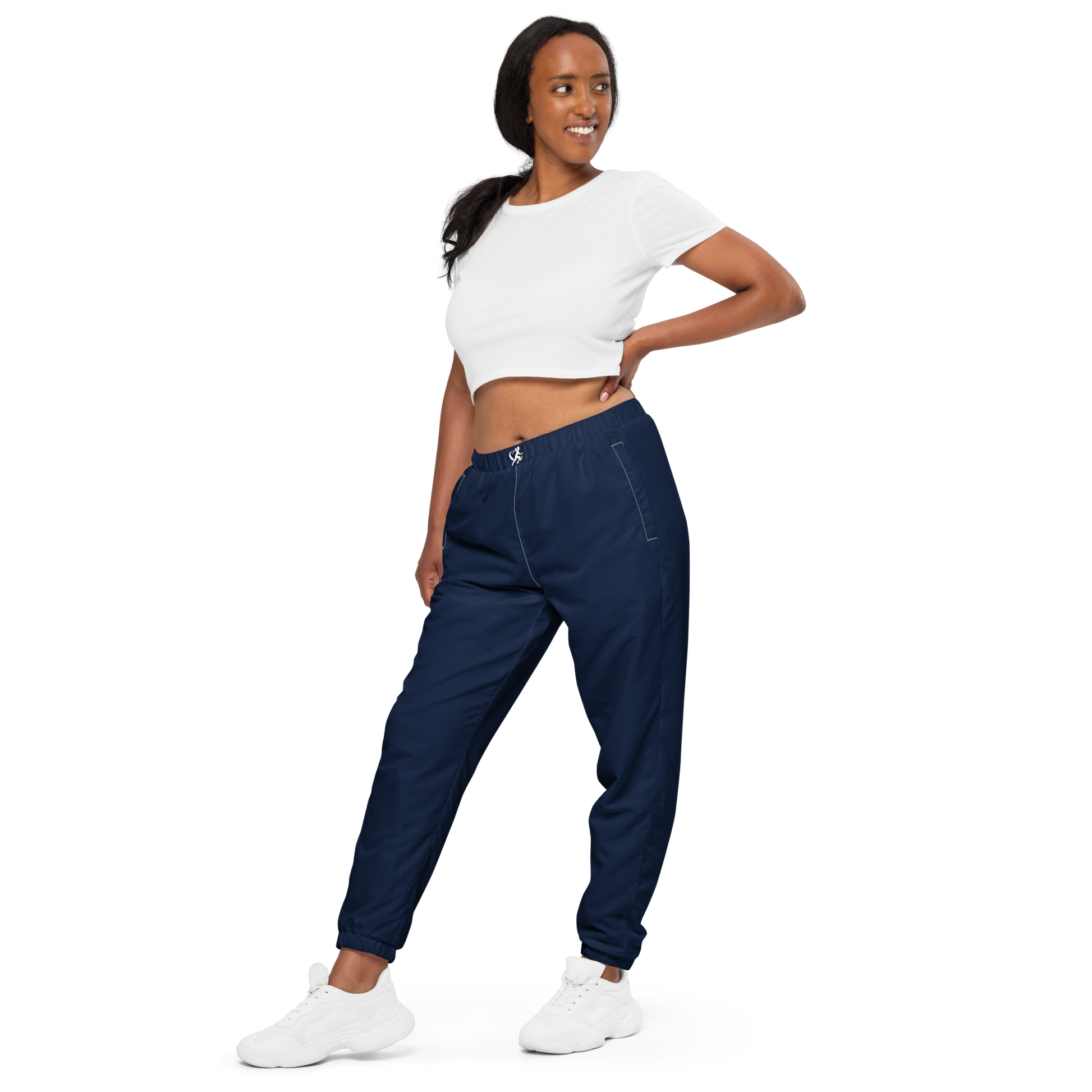 Woman wearing navy jogger pants and a white crop top on a white background