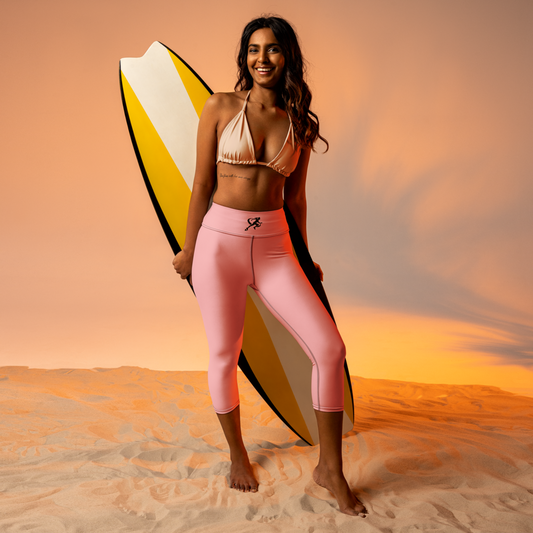 Woman holding a surfboard on a beach with a sunset background