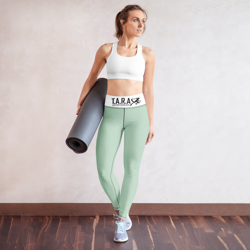 Woman in a yoga pose wearing a white sports bra and green leggings with 'TARA' branding on a white background