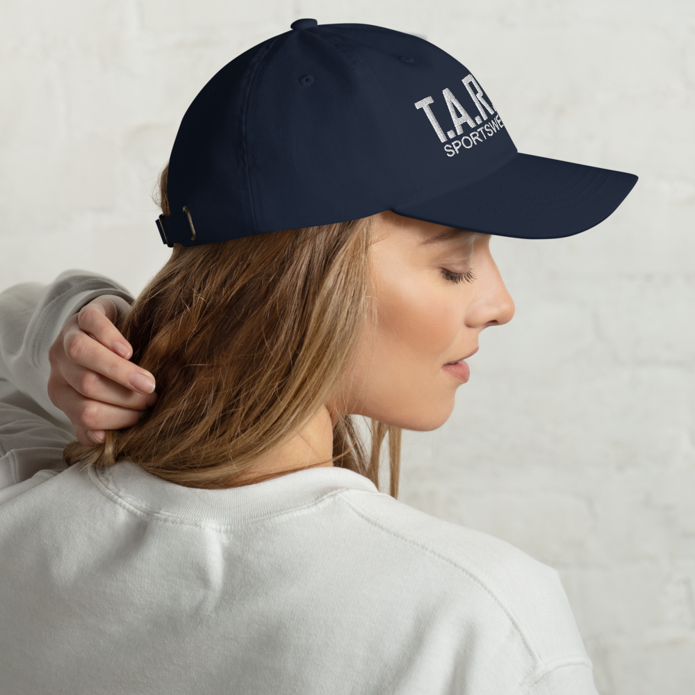 A woman wearing a navy blue cap with the logo 'T.A.R.A Sportswear' on the front.