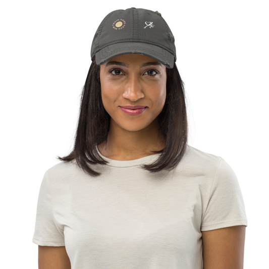 Woman wearing a dark gray cap with embroidered designs on a white background