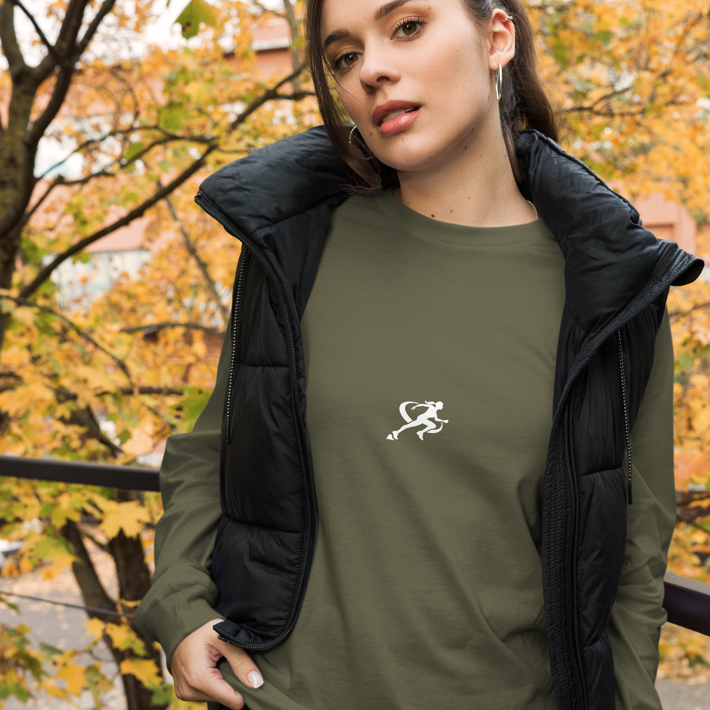 A woman wearing a military green long-sleeved crew neck t-shirt with a small white logo on the chest.