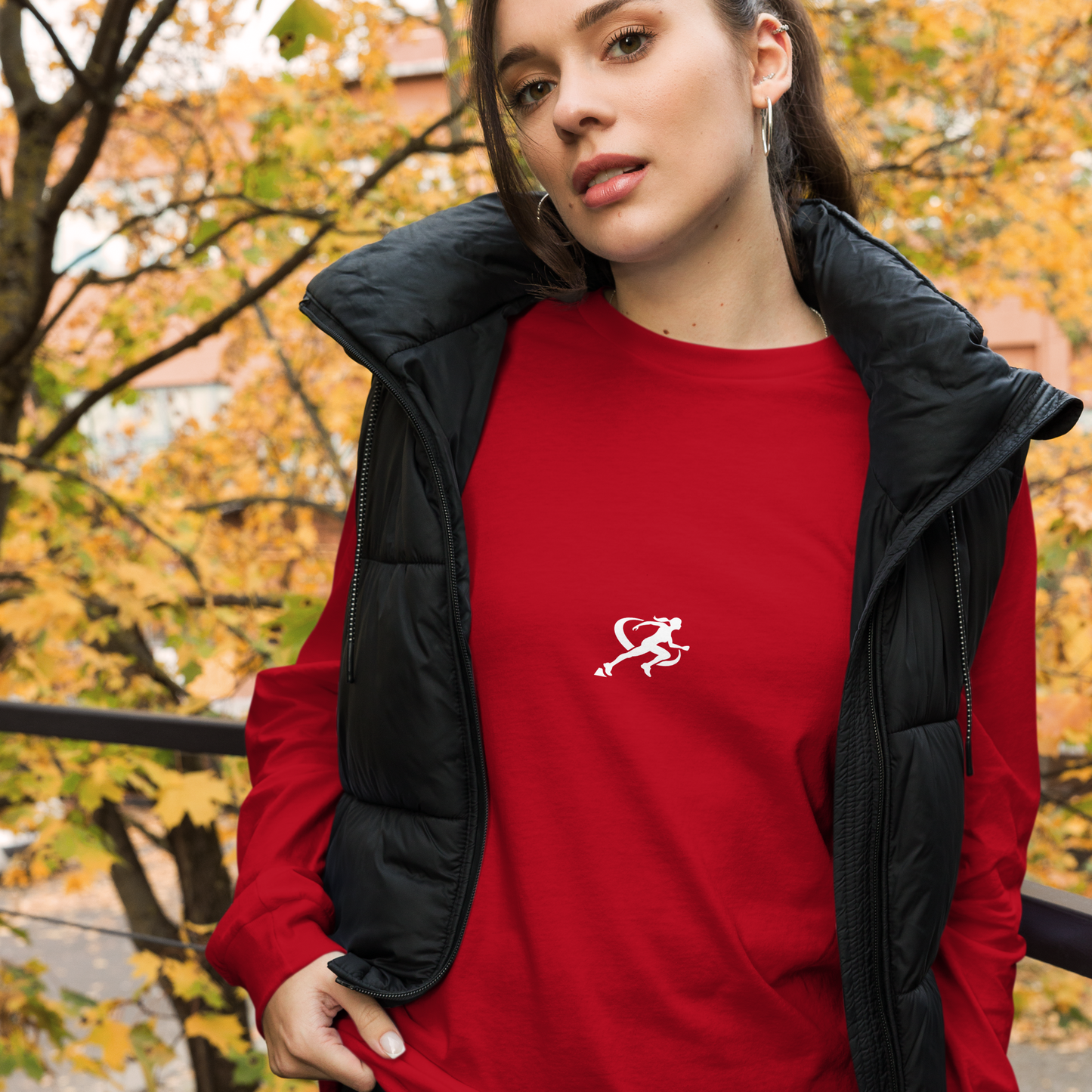 A woman wearing a red long-sleeved crew neck t-shirt with a small white logo on the chest.