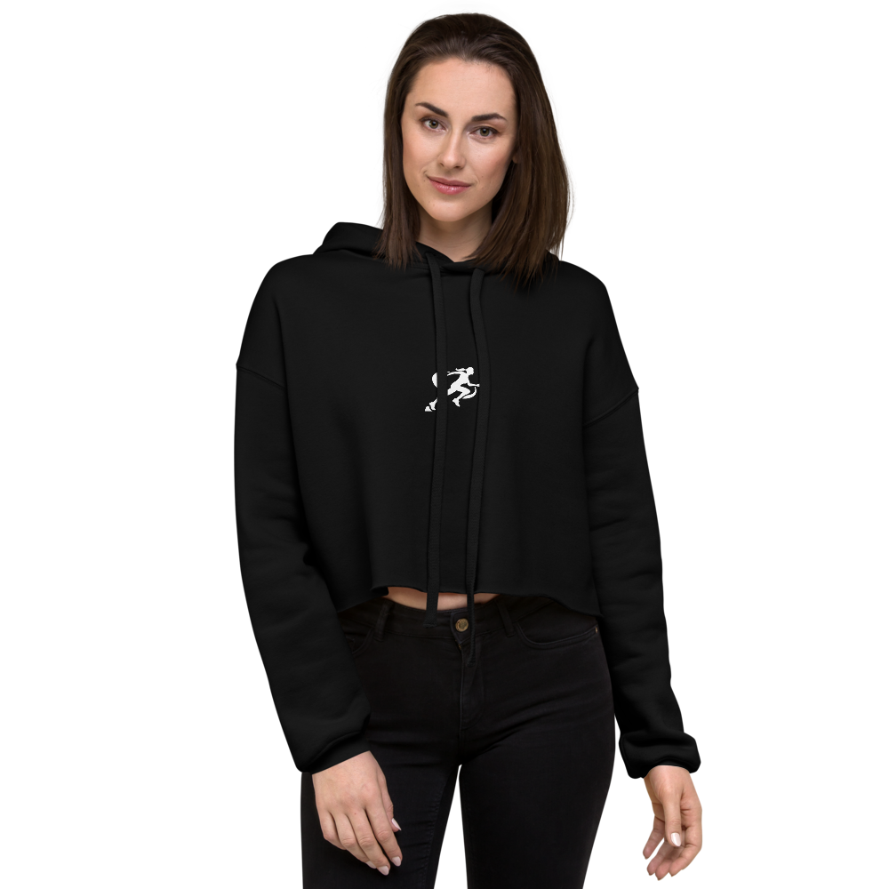 A woman wearing a black cropped hoodie with a graphic on the front standing against a neutral background.