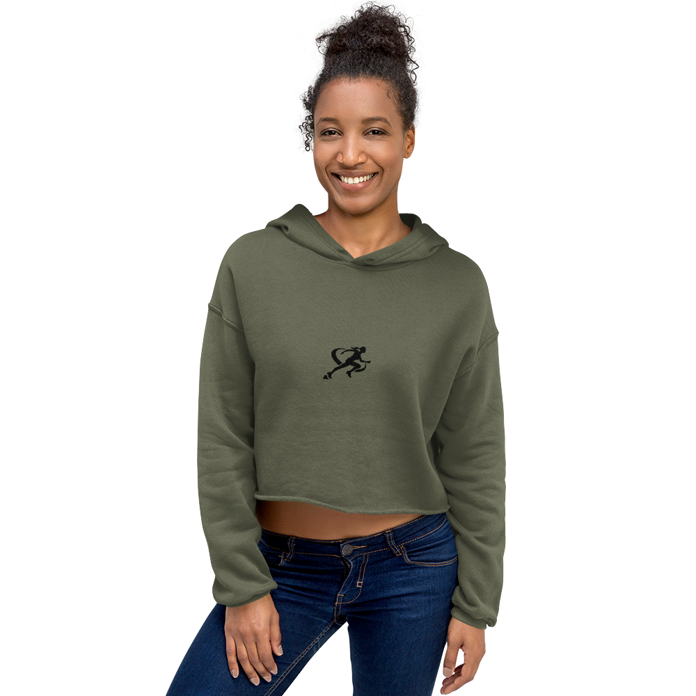 A woman wearing a military green cropped hoodie with a graphic on the front standing against a neutral background.